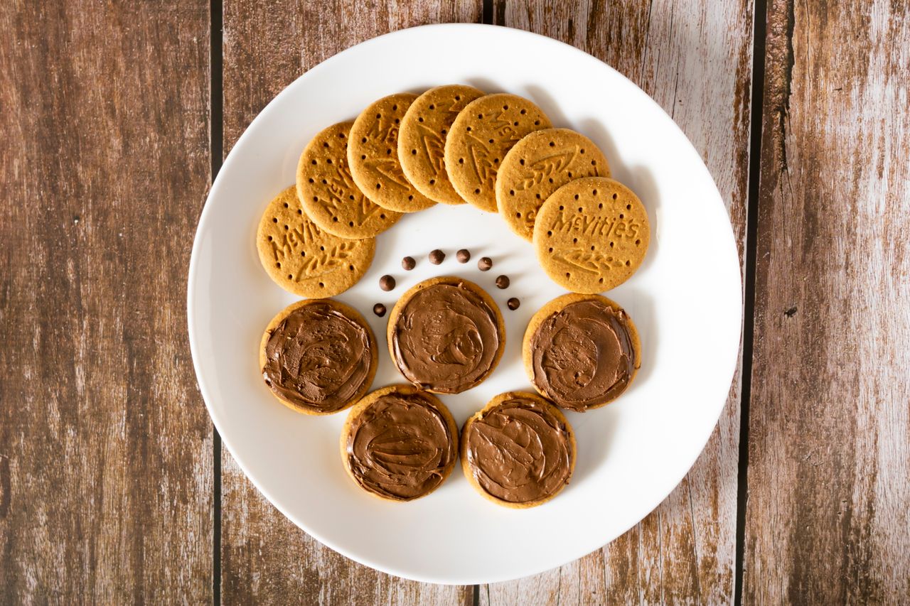 Top view of chocolate spread biscuits arranged creatively on a white plate.